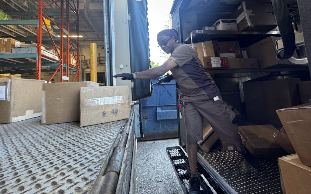 Man unloading packages in the back of a UPS electric truck