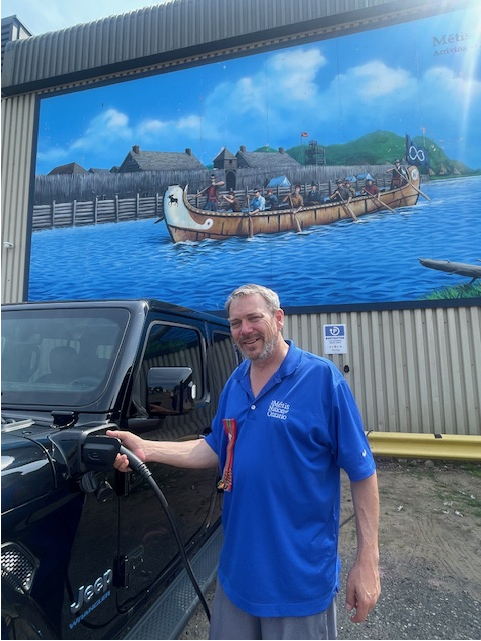 Man holding an EV charger beside a truck